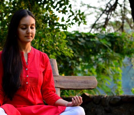 A young woman meditating on a bench in the woods