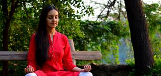 A young woman meditating on a bench in the woods